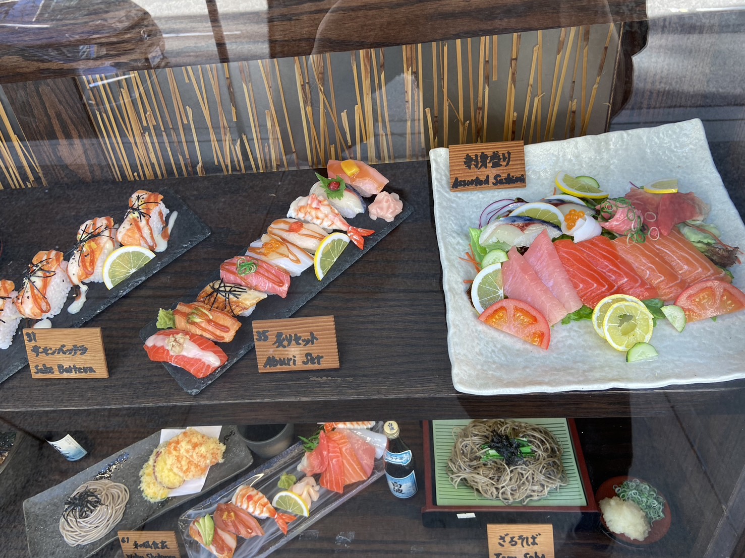 A glossed and lit sushi and sashimi platter food replica in a restaurant window